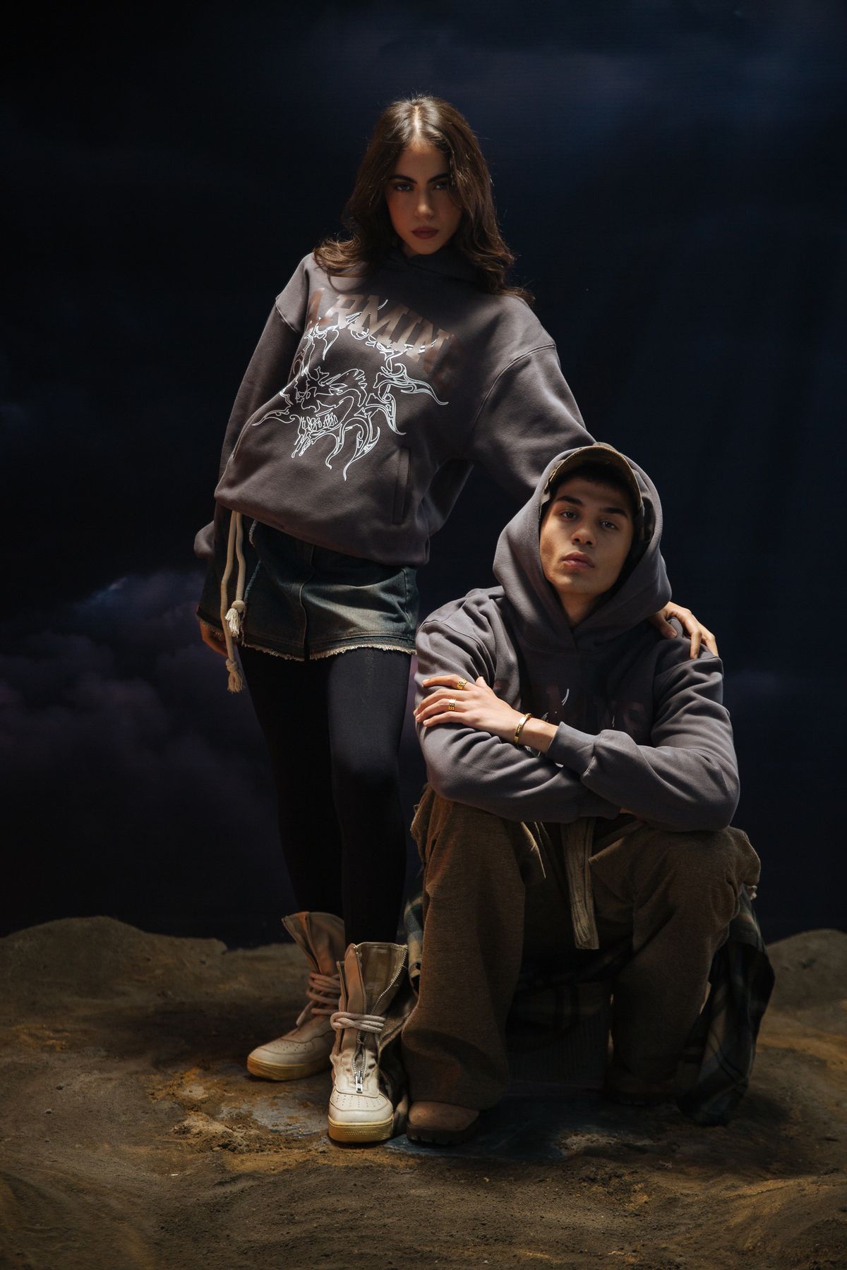 Two models in grey graphic hoodies on sand