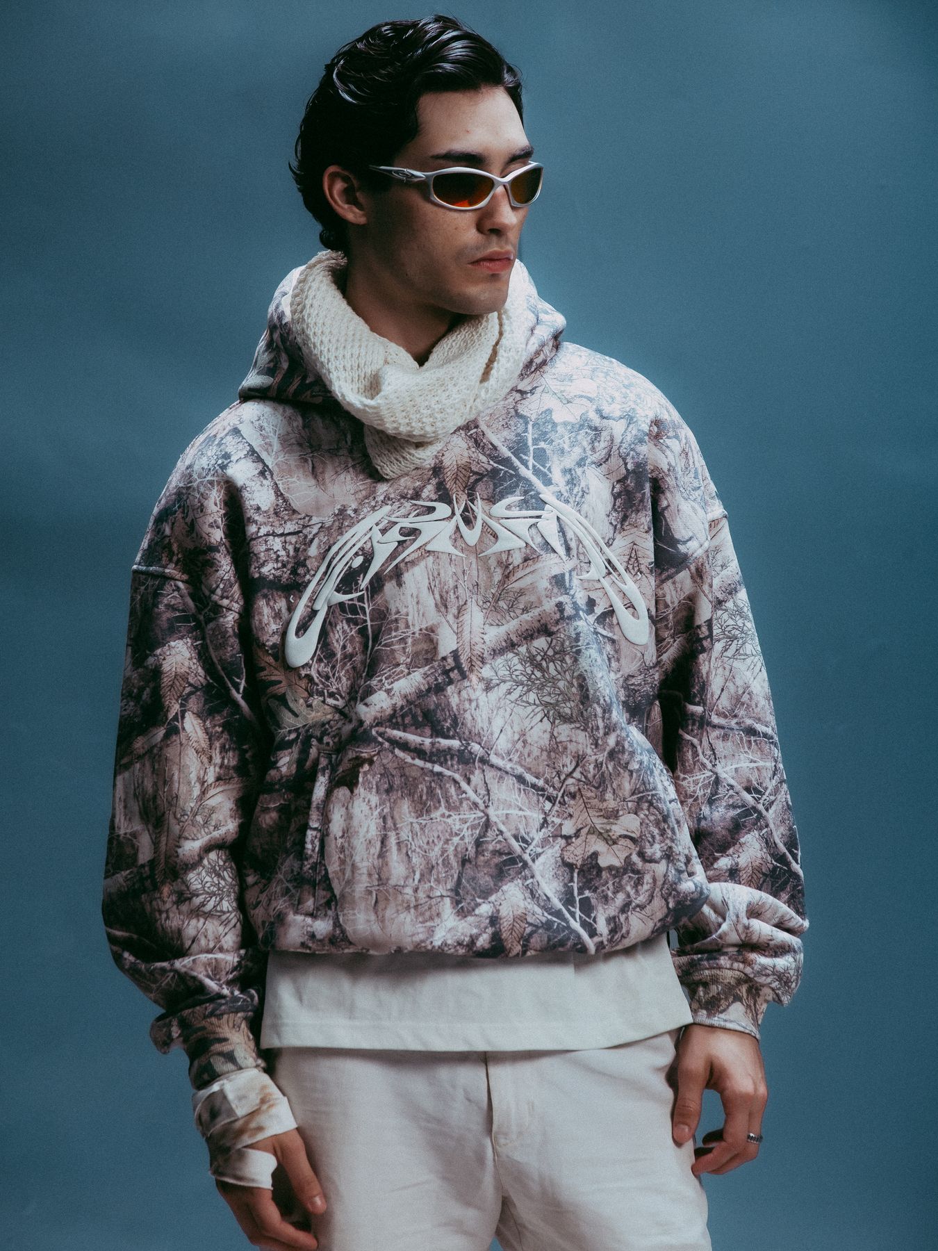 Model in a camouflage hoodie and sunglasses